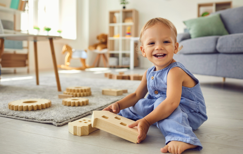 smiling toddler plays with blocks on floor